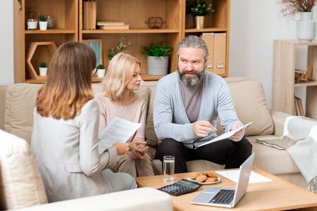 Bearded man looking through paper while consulting with real estate agentの写真素材