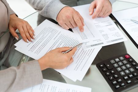 Hands of agent and mature man pointing at financial documents