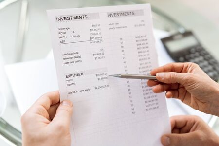 Human hand holding pen while pointing at sum of money in financial documentの写真素材