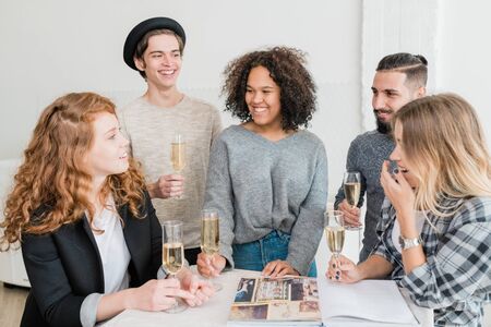 Laughing friends with champagne looking at one of girls telling funny stuff