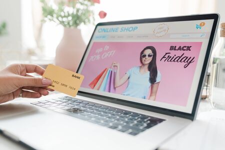 Laptop display with black friday screensaver and female hand with credit cardの写真素材