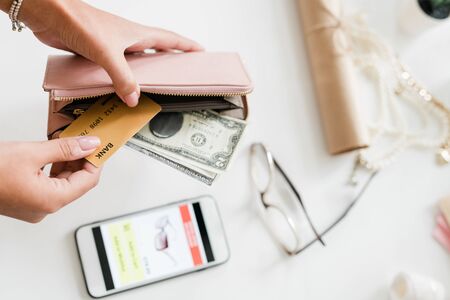 Hands of young woman holding leather wallet with dollar bills and plastic cardの写真素材