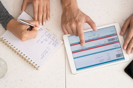 Human hands during discussion of online information in touchpad and making notes