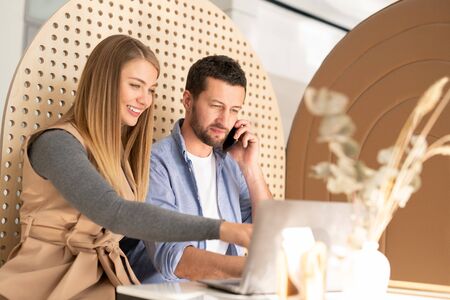 Smiling businesswoman making presentation to busy colleague with smartphone