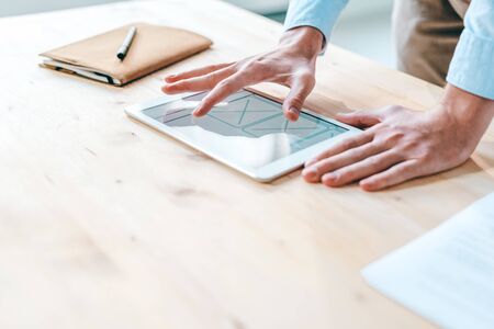 Young contemporary webdesigner pointing at application design on touchpad screen while working over...