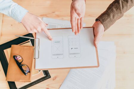 Overview of clipboard with interface or program application on paper being discussed by two...