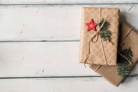 Stack of two wrapped giftboxes bound with threads on white table that can be used as Christmas...