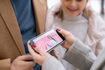 Female hands holding smartphone with home page of online shop