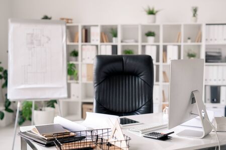 Workplace of architect or office manager with desk, black leather armchair, whiteboard, computer...