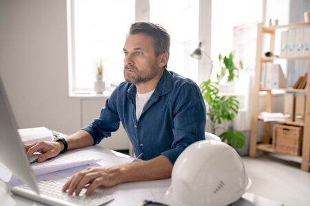 Serious engineer concentrating on work while sitting in front of computer screen