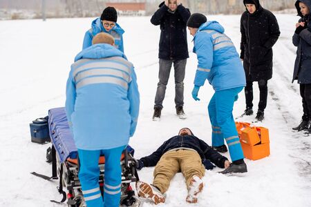Brigade of young paramedics in uniform pushing stretcher towards unconscious manの写真素材