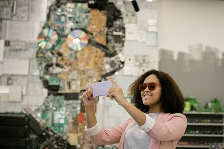 Young cheerful female in sunglasses making selfie in contemporary optics shop