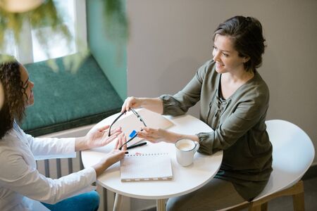 Woman looking at optics clinician while going to buy pair of new eyeglassesの写真素材