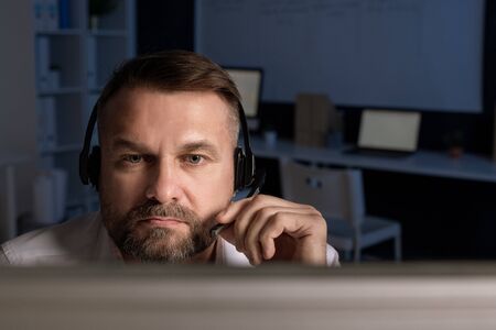 Confident customer support representative with headset speaking in microphoneの写真素材