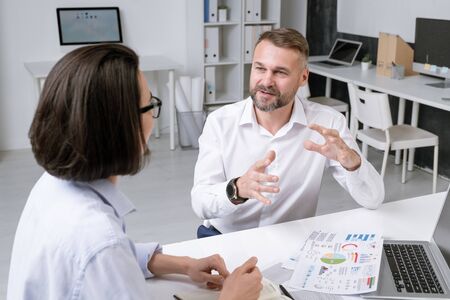Confident mature broker explaining his idea to young female colleagueの写真素材