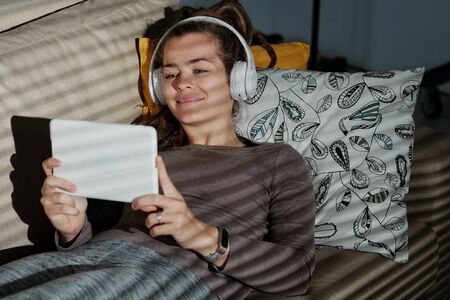 Happy young female relaxing on couch while watching funny video