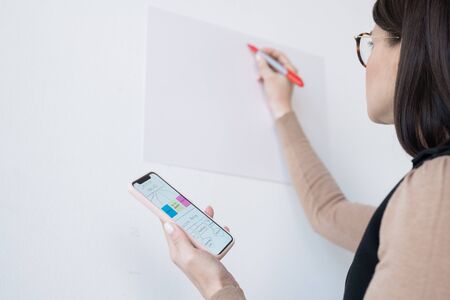 Young businesswoman or coach holding smartphone with flow chart