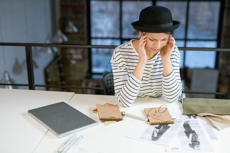 Tired designer in casualwear trying to concentrate while thinking of new ideas