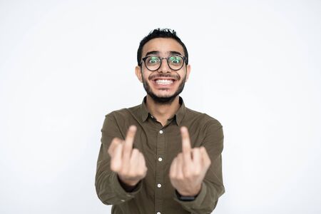 Spiteful young man with toothy smile showing you indicent gesture in isolation
