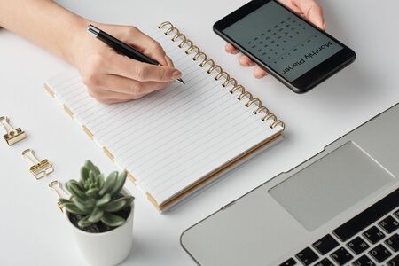 Hand of contemporary businesswoman with pen over blank page of notebookの写真素材