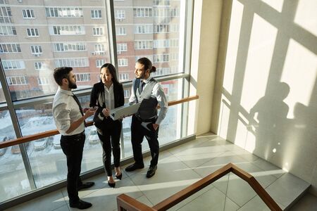 Group of three young contemporary analysts in formalwear discussing online data