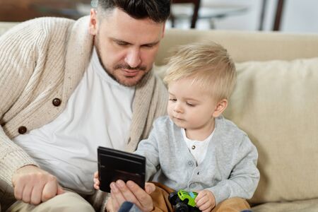Young man with little boy using gadget