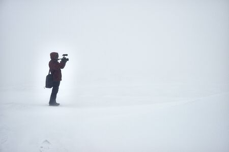 Lonely photographer with photocamera shooting in winter fieldの写真素材