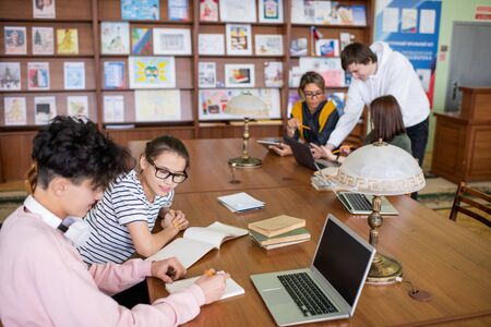 Two small groups of contemporary college students discussing points of projects