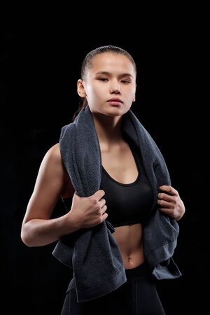 Pretty young female in black sportswear holding grey soft towel on her neckの写真素材