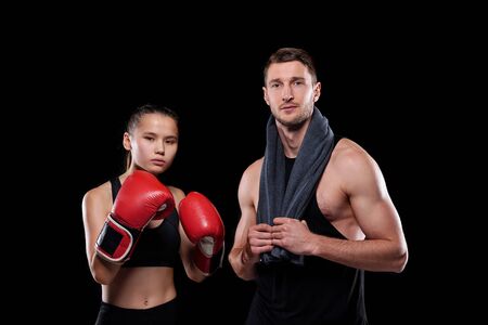 Sporty girl in red boxing gloves and her muscular boyfriend with towel