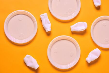 Horizontal from above flat lay shot of white plastic empty plates and bottles lying on orange surfaceの写真素材
