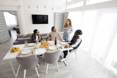 Group of young multi-ethnic friends gathering together to drink wine at home