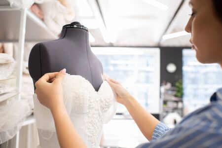 Professional seamstress working on wedding dress corset in bridal workshop, horizontal shotの写真素材