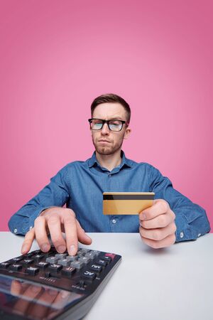 Portrait of cheerful successful young man in jacket making finger guns against blue backgroundの写真素材
