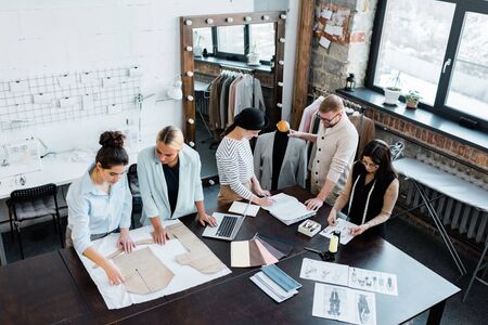 Two groups of professional fashion designers working with sketches and patterns
