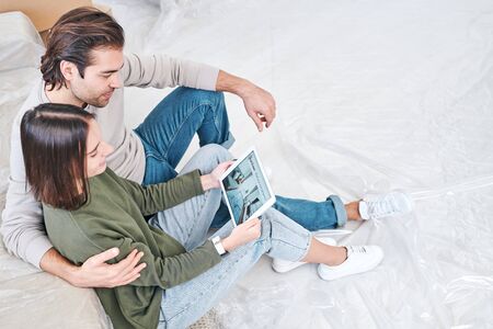 Husband and wife with touchpad looking through online ideas of new flat planning
