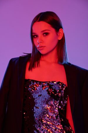Pretty girl with smooth long hair wearing glittering dress and black jacket