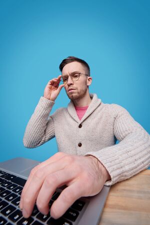 Hand of young serious businessman on laptop keypad during online search