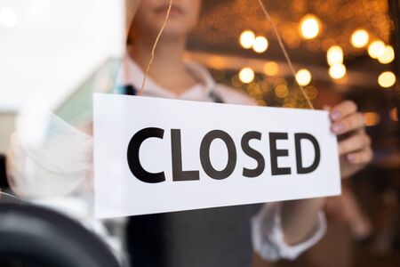 Paper with notice closed behind door of cafe on background of young waitressの写真素材