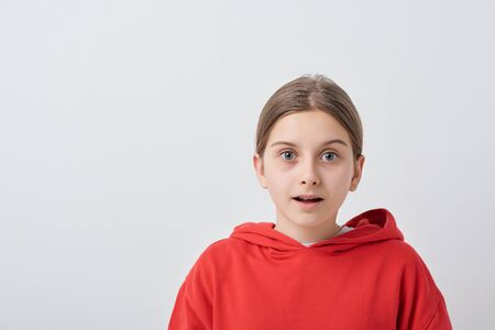 Scared or surprised teenage girl in red hoodie standing in front of camera