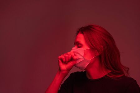 Young sick female with covid19 in protective mask coughing in isolationの写真素材