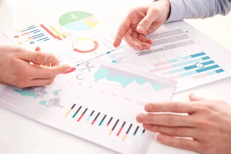 Close-up of unrecognizable business colleagues comparing charts while discussing finances of companyの写真素材