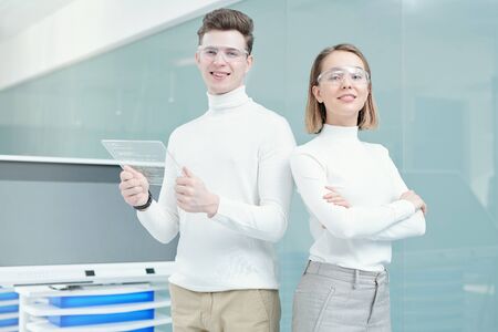Two young smiling programmers in smart casualwear and goggles looking at youの写真素材