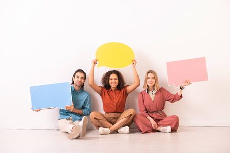 Portrait of positive multi-ethnic people sitting with speech bubble tags, they staying socially...