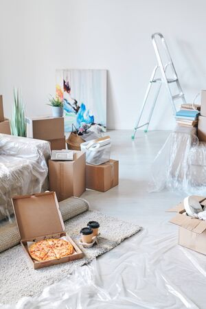 Open box with delivered appetizing pizza and two glasses of coffee on the floor
