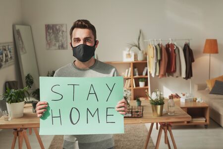Young sick man with black mask on face recommending you to stay homeの写真素材