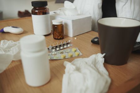 Wooden table with brown mug, paper tissues and variety of medicineの写真素材