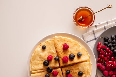 Flatlay of kitchen table with appetizing pancakes with fresh berries and honeyの写真素材