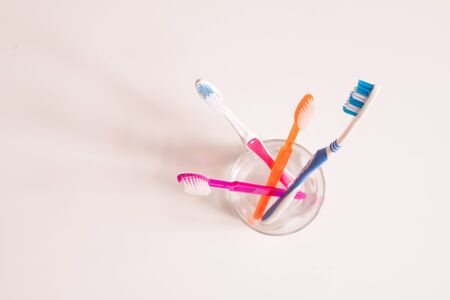 Overview of glass with bunch of new blue, orange and pink toothbrushesの写真素材