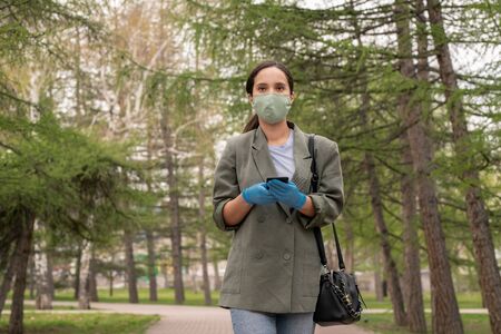 Young brunette woman in protective gloves and mask looking at youの写真素材
